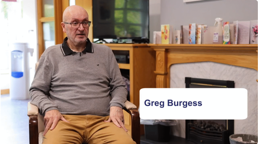 A man sits on a chair in front of a fireplace